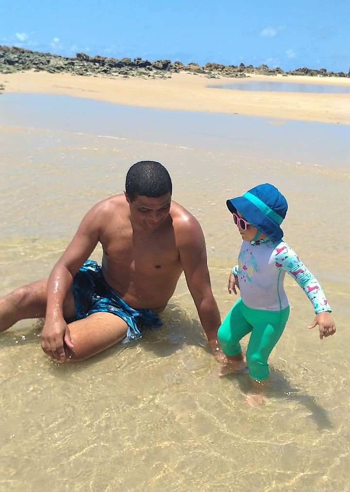pai e filhinha de 2 anos brincando na beira da praia de joao pessoa. Clientes da Suez Turismo