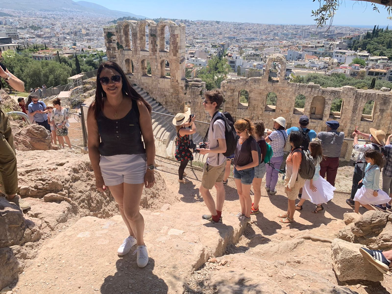 mulher posando para foto numa viagem a grécia, nos fundos as ruinas gregas. Clientes da Suez Turismo